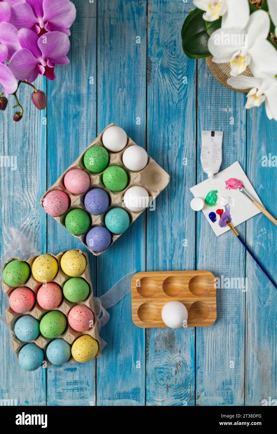 Multicolored easter eggs on blue table with paint brushes and paint Stock Photo
