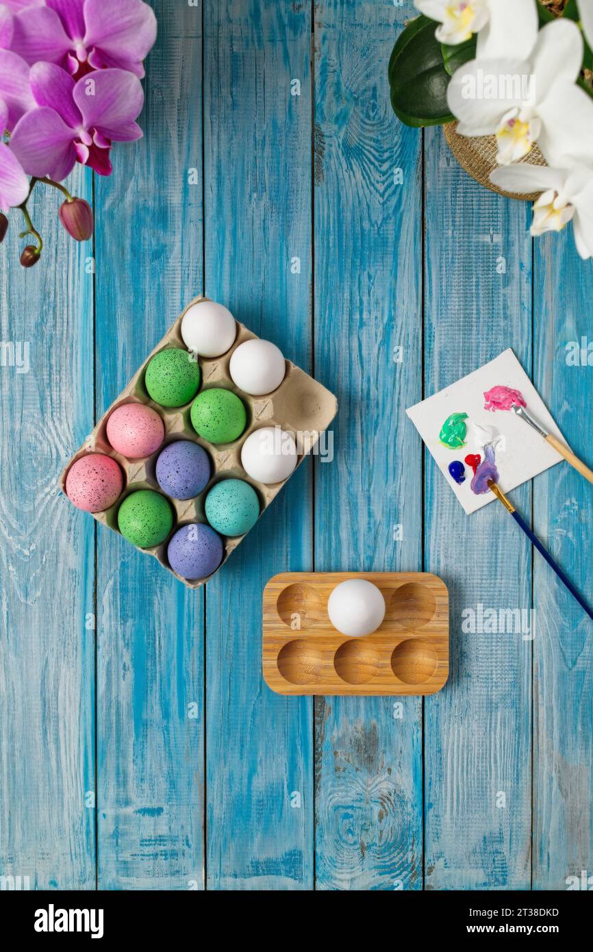Multicolored easter eggs on blue table with paint brushes and paint Stock Photo