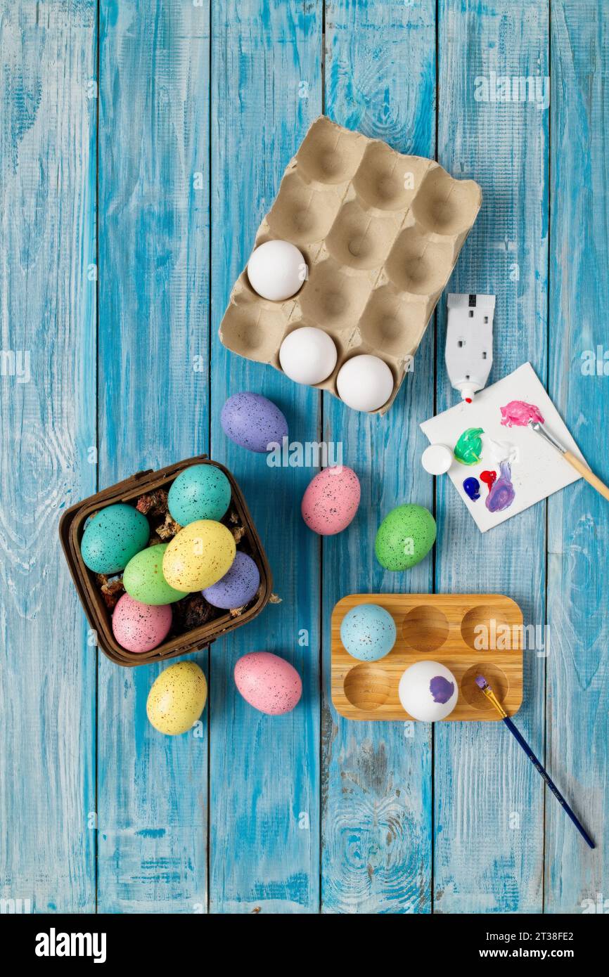 Multiple multicolored easter eggs, painting an egg purple with paint brush Stock Photo
