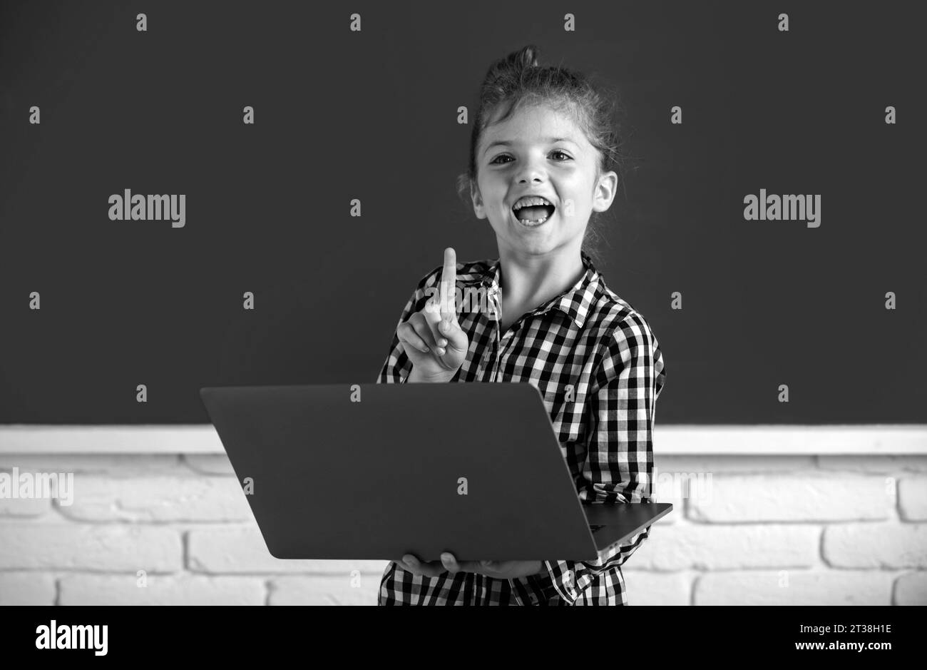 School child girl using digital pc laptop in class. Portrait of funny ...