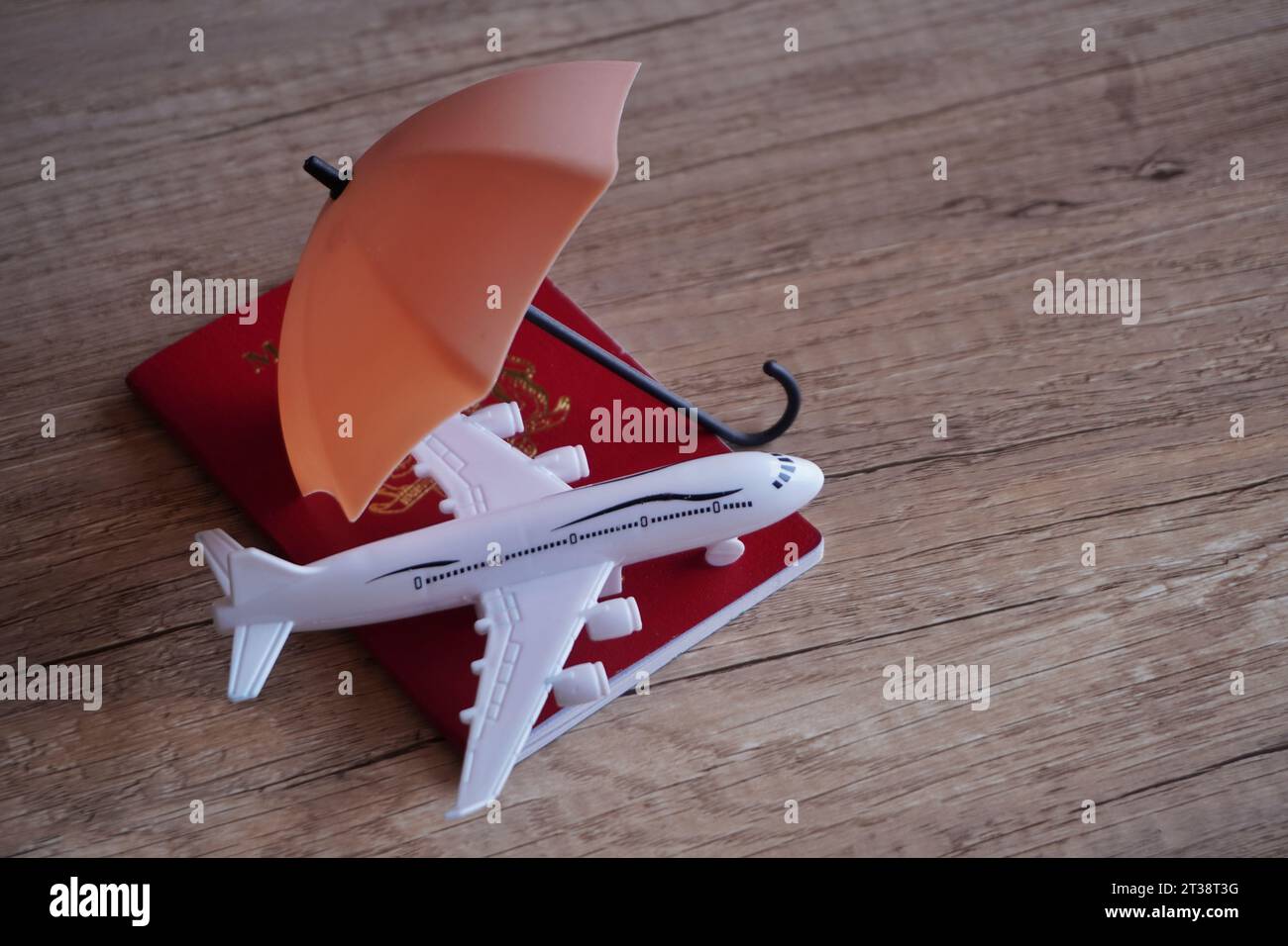 Closeup image of toy plane, passport and umbrella on table with copy space. Travel insurance concept. Stock Photo