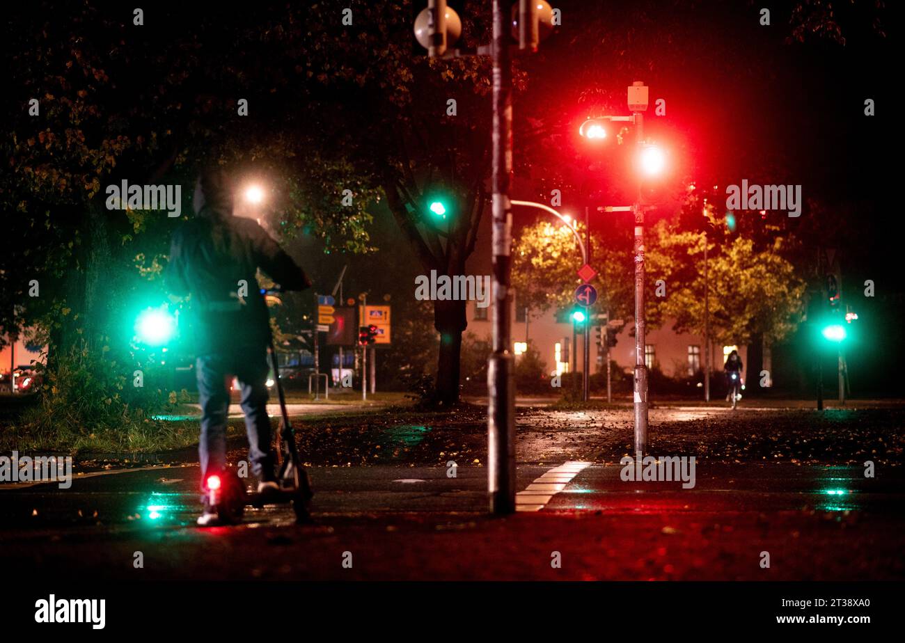 Oldenburg, Germany. 24th Oct, 2023. A young man is standing in front of a red light at the