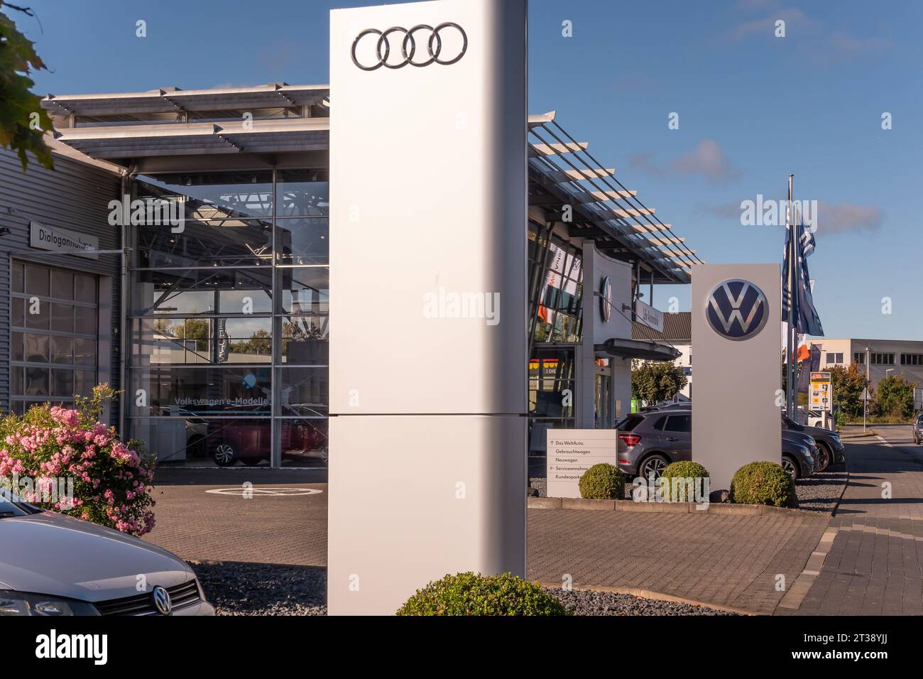 Neuwied, Germany -October 21, 2023:  a pylon with the AUDI logo in front of another one with  the VW logo (Volkswagen) and the showroom of the local A Stock Photo