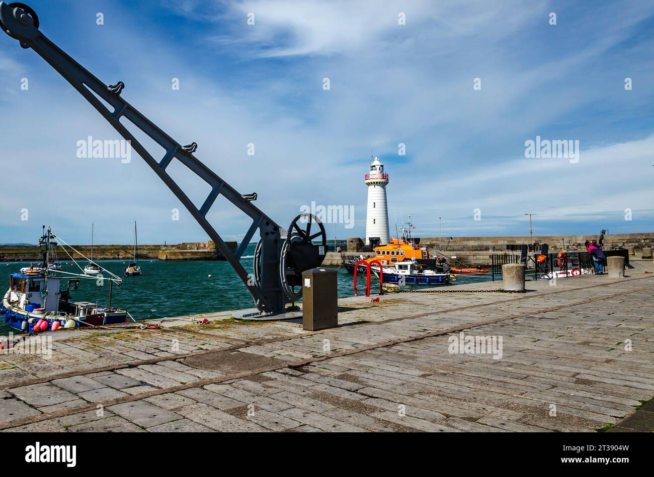 Donaghadee, County Down, Northern Ireland, August 05 2023 - Donaghadee lighthouse with  RNLI lifeboat in the harbour and old crane with copy space Stock Photo