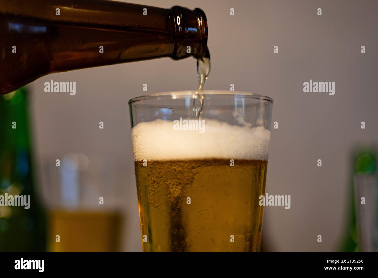 Close-Up. Pouring Beer In Glass. Beer is poured from dark brown bottle into beer glass. Stock Photo