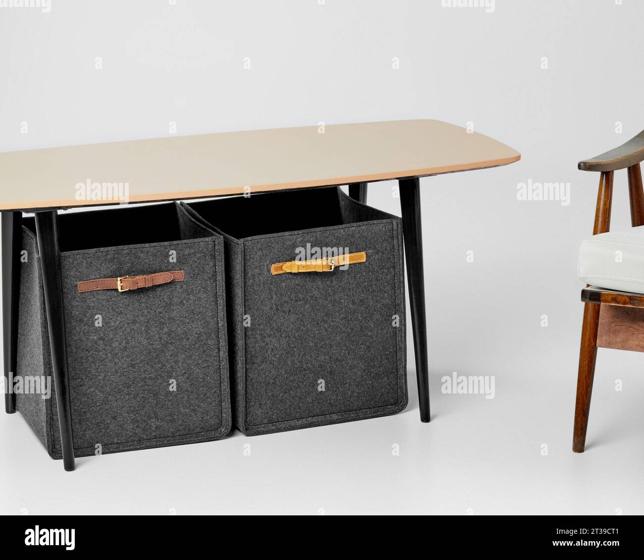 Two gray felt storage boxes with leather handles standing under table Stock Photo