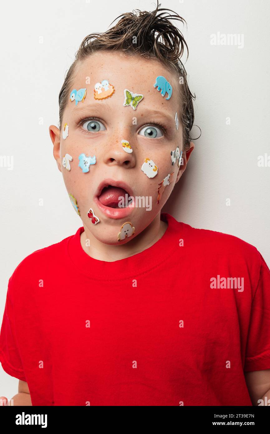 A young boy with wet hair sticks out his tongue and has colorful animal