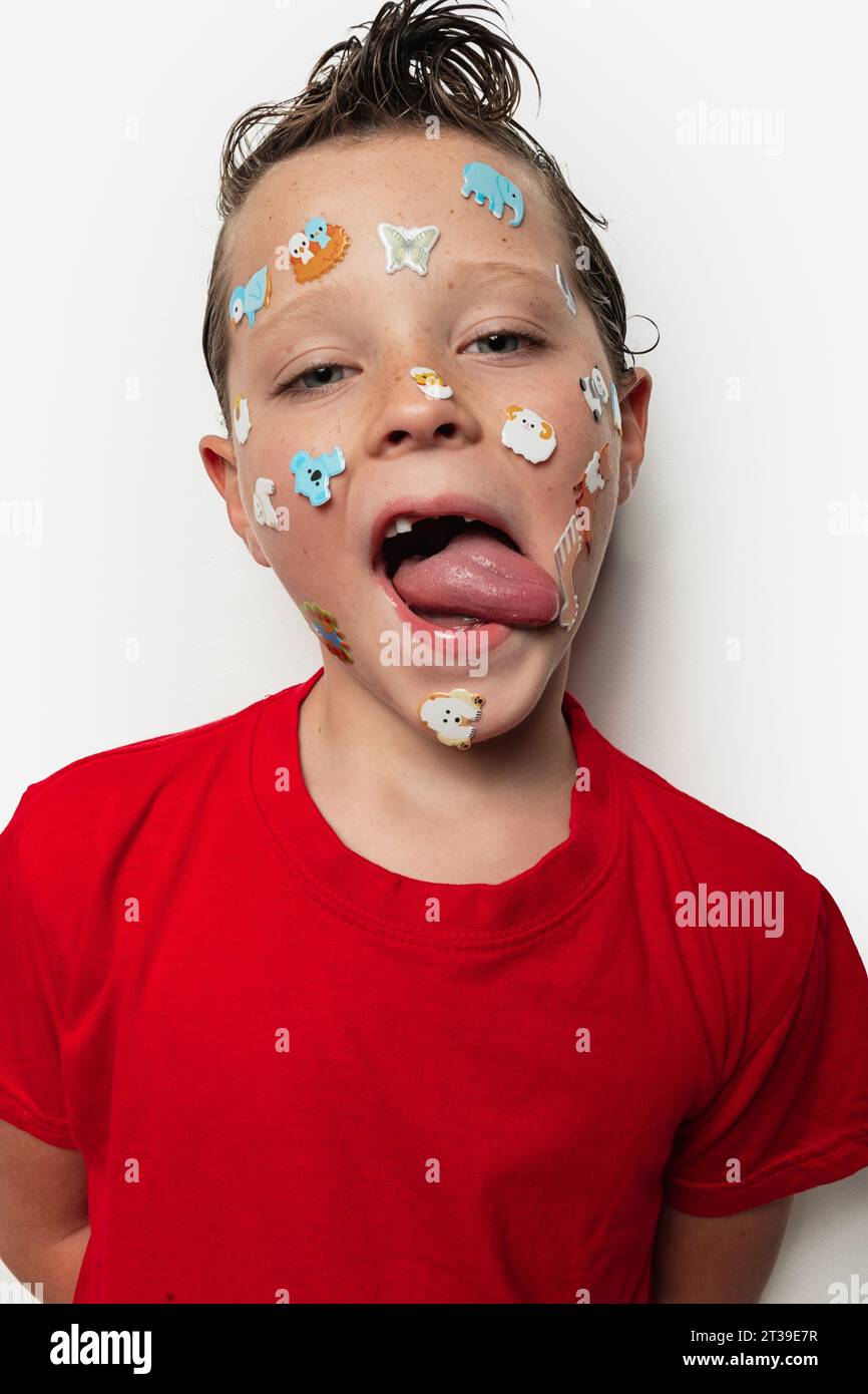 A young boy with wet hair sticks out his tongue and has colorful animal