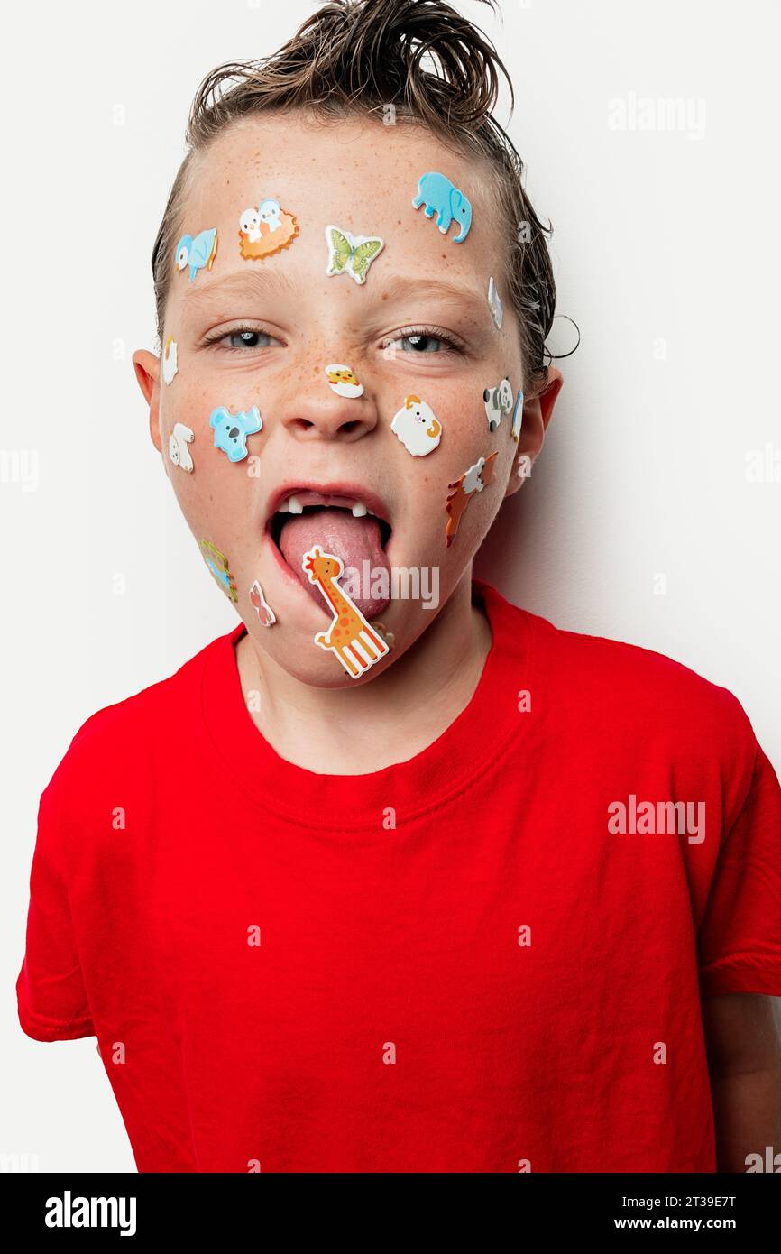 A young boy with wet hair sticks out his tongue and has colorful animal