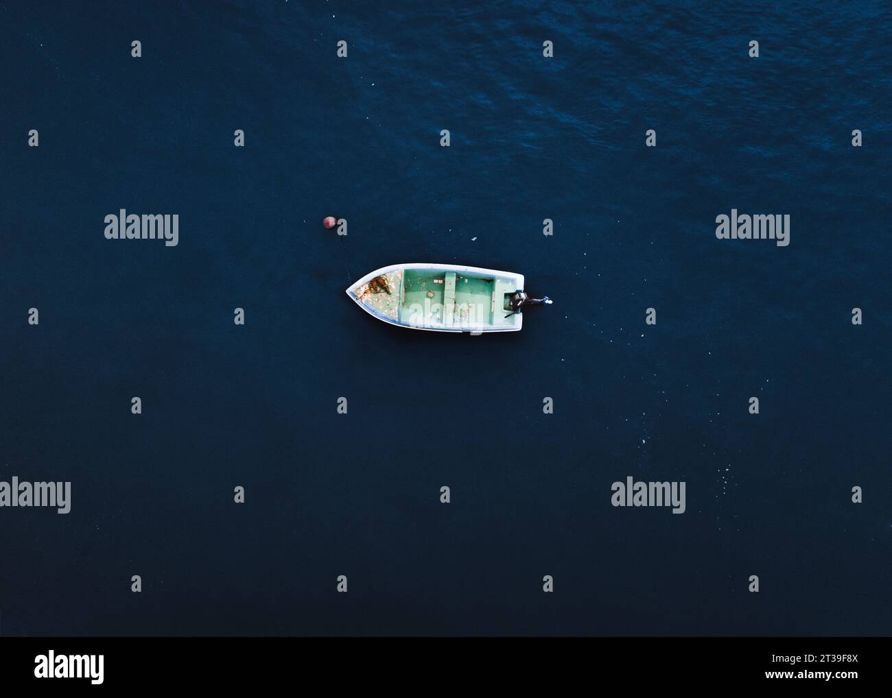 Aerial top view of a small fishing boat with equipment moored in dark ...