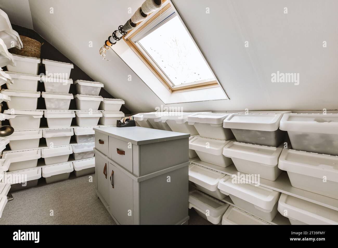 https://c8.alamy.com/comp/2T39FMY/wooden-cabinet-and-white-plastic-boxes-stacked-and-arranged-by-bright-window-in-attic-room-at-home-2T39FMY.jpg