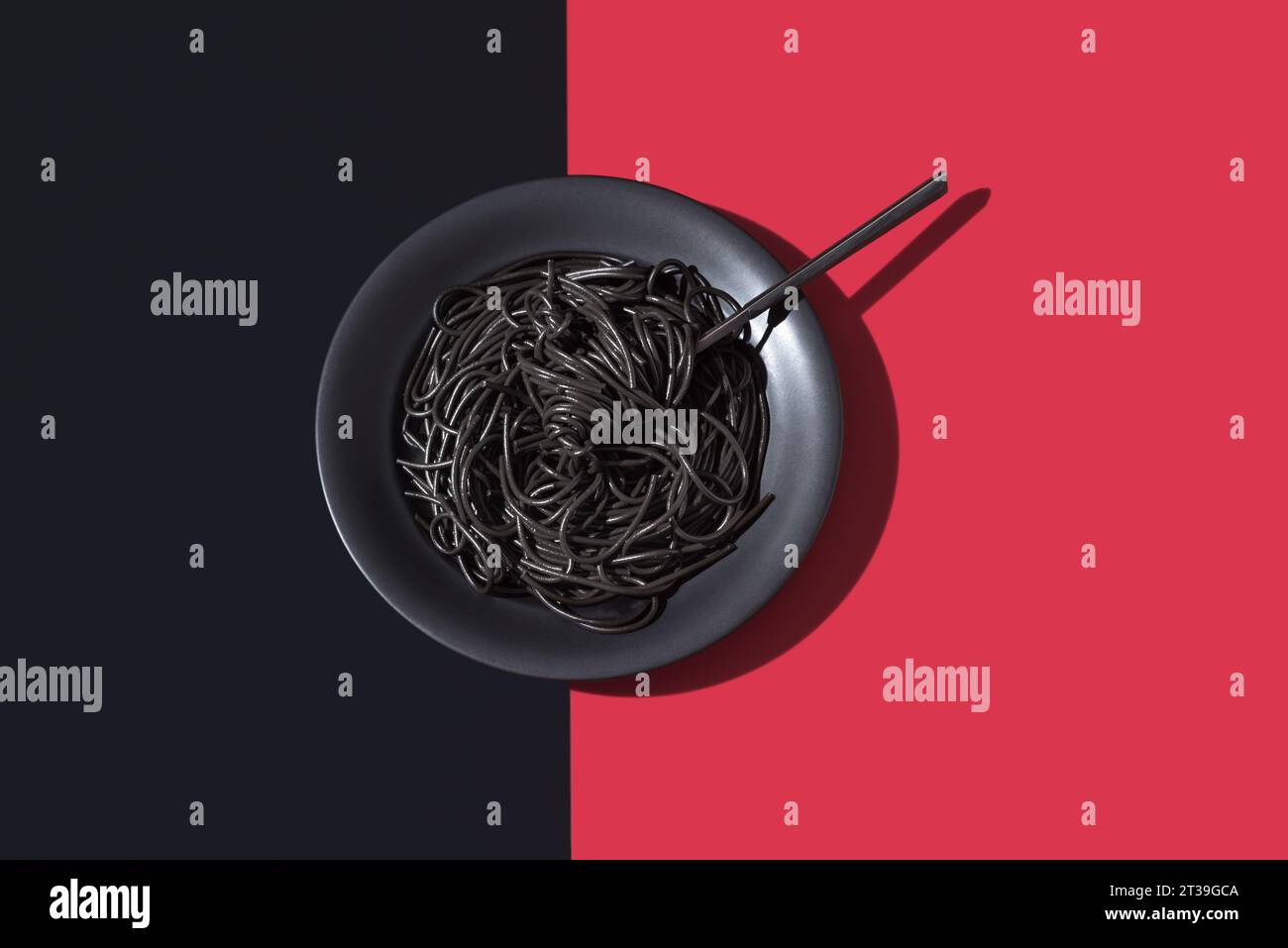 Top view of black spaghetti in a bowl with fork placed on black and red background Stock Photo