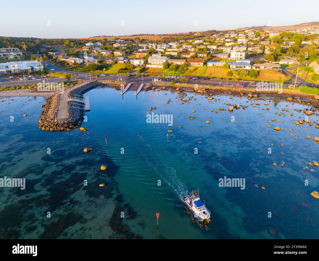 Aerial view of a fishing boat leaving a boat ramp along a residential