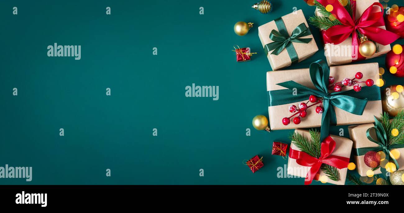 Holiday green background with gift boxes tied with silk ribbons and Christmas decorations. Christmas holiday background. Top view with copy space. Stock Photo