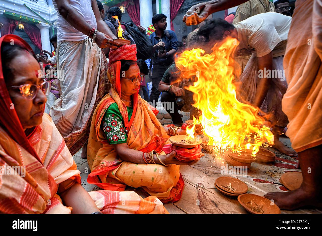 Kolkata, India. 22nd Oct, 2023. An Indian Hindu woman sits with burning fire pots on her hands and head as part of their ritual practice which includes blind faith and superstition to overcome every difficulties in coming future during the Maha ashtami celebration on the 8th day of Durga puja. Durga puja is the biggest Hindu festival running for 9 days all over India. Credit: SOPA Images Limited/Alamy Live News Stock Photo