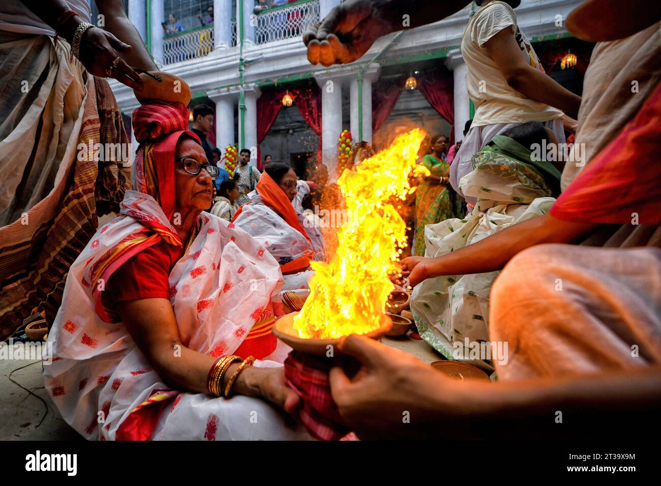 Kolkata, India. 22nd Oct, 2023. An Indian Hindu woman sits with burning fire pots on her hands and head as part of their ritual practice which includes blind faith and superstition to overcome every difficulties in coming future during the Maha ashtami celebration on the 8th day of Durga puja. Durga puja is the biggest Hindu festival running for 9 days all over India. Credit: SOPA Images Limited/Alamy Live News Stock Photo