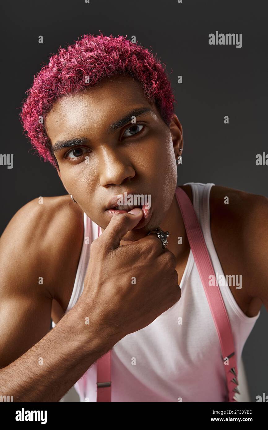 portrait of stylish pink haired man with hand on his face and lip ...