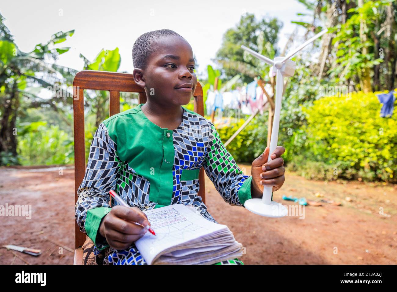 Young African student reviews his lessons on the wind turbine. Wind energy concept. Stock Photo