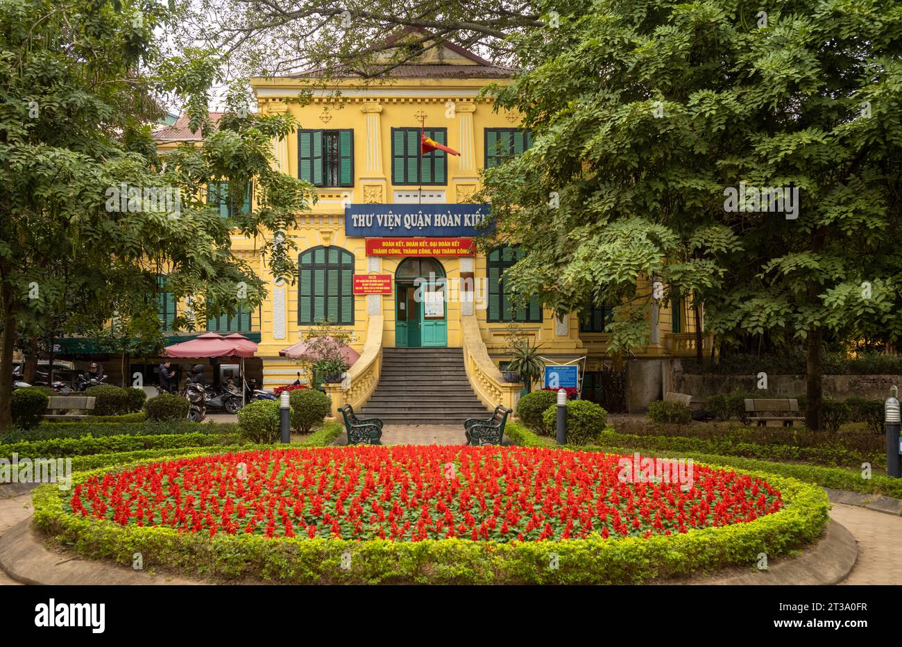 The grand French colonial building housing the Hoan Kiem District Library with ornate flowers beds in the park in front, Hanoi, Vietnam. Stock Photo