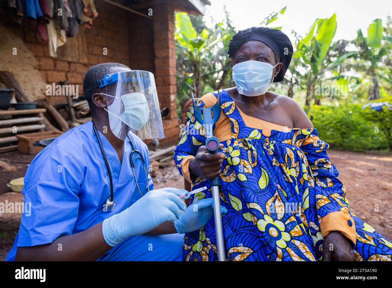 Young African doctor prepares to inject a dose of vaccine into a sick old woman. Stock Photo