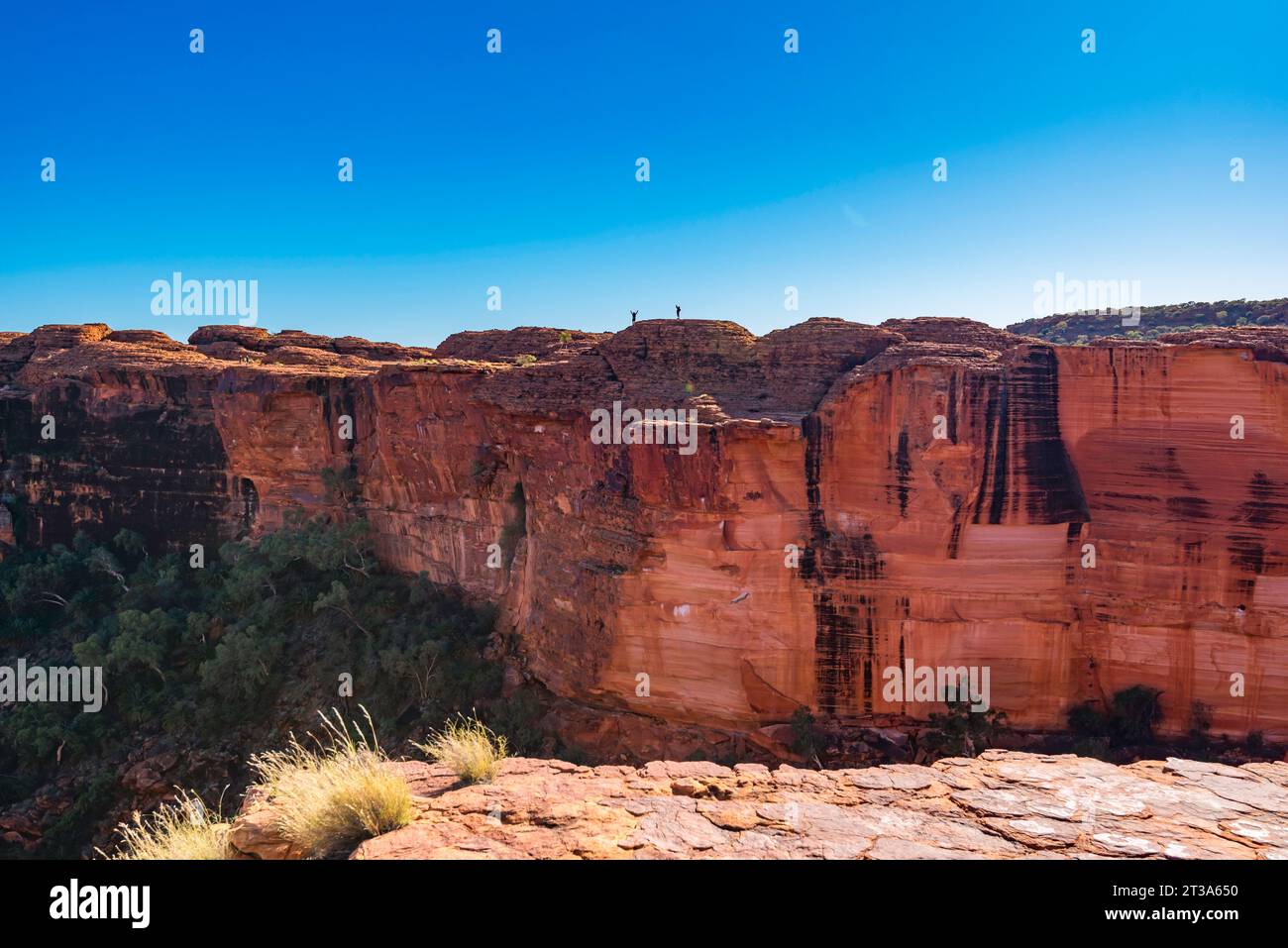 Two men waving from the rock domes near the northern cliff wall of Kings Canyon (Watarrka) in the Northern Territory of Australia Stock Photo