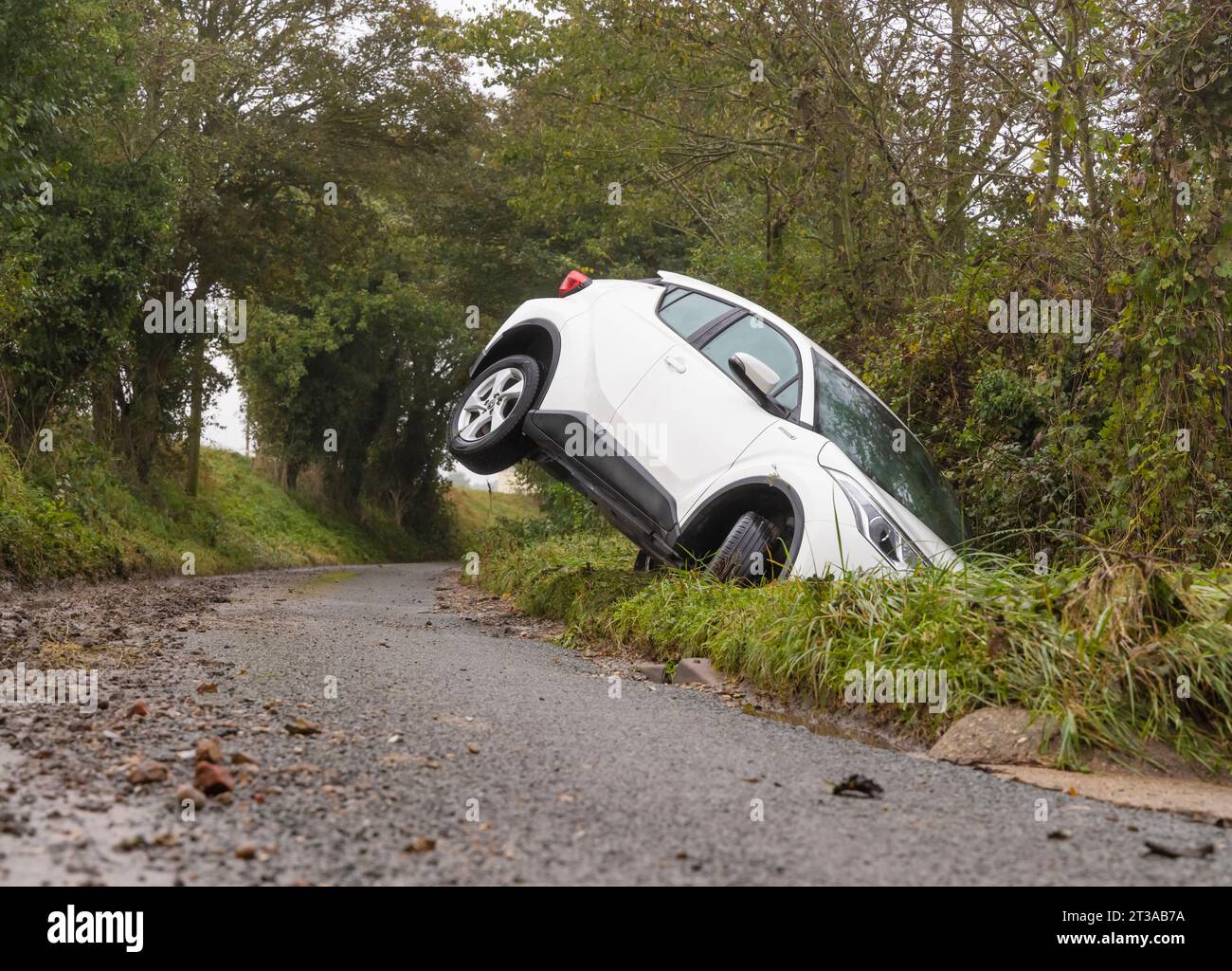 Abandoned white car in a ditch in a country lane following Storm Babet. UK Stock Photo