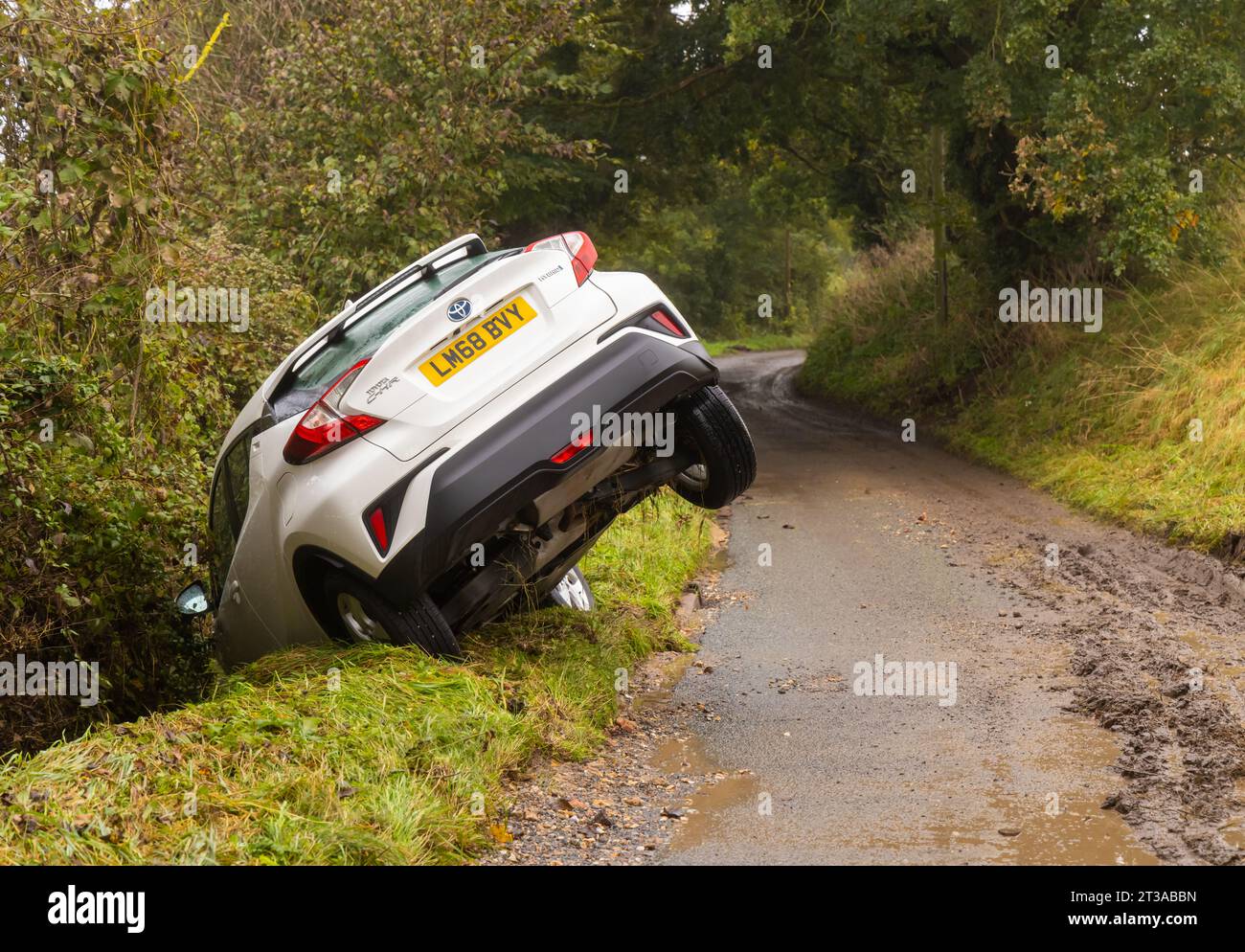 Abandoned white car in a ditch in a country lane following Storm Babet ...