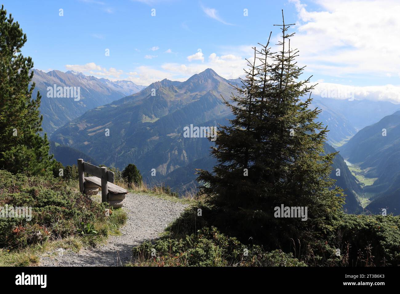a wooden bench in the mountains invites hikers to take a break Stock Photo