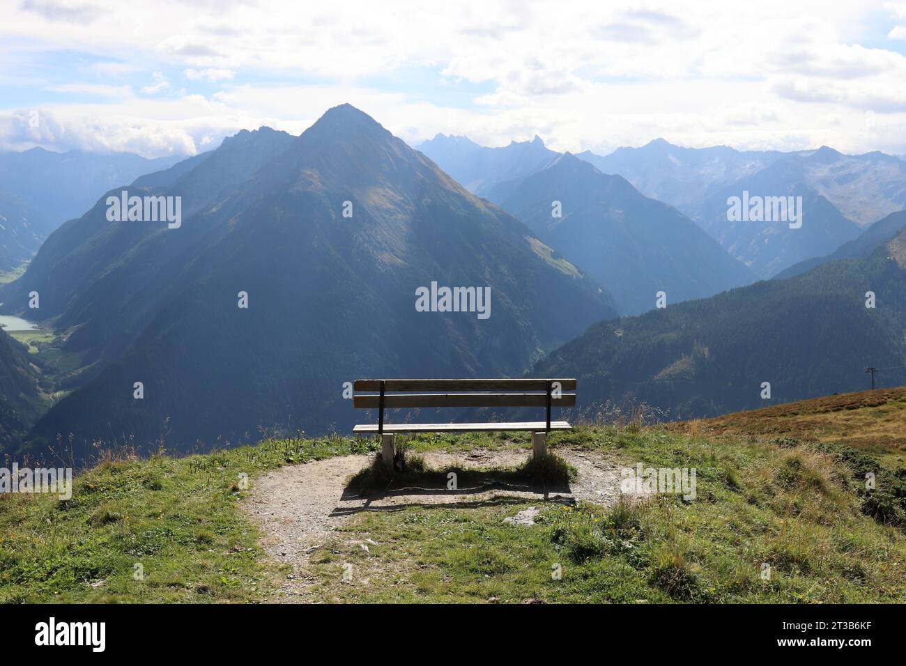View of a wooden bench on a mountain plateau in front of a magnificent mountain backdrop Stock Photo