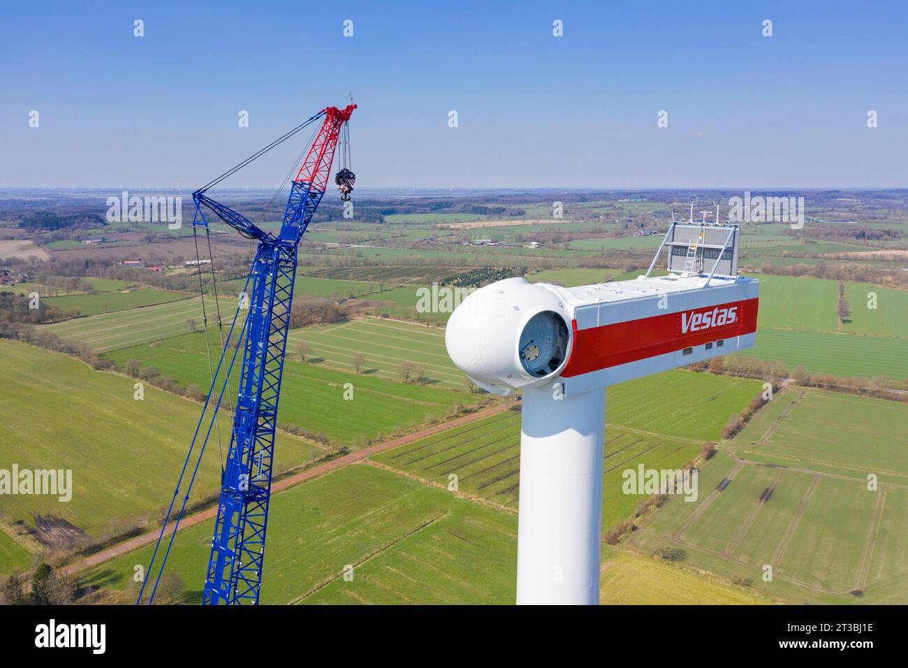 Construction crane assembling wind turbine at windfarm showing mounted nacelle with rotor hub Stock Photo
