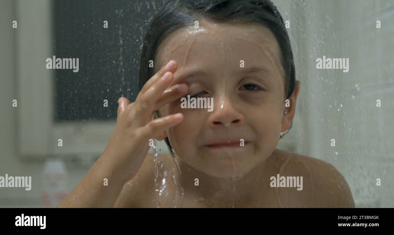 Closeup young boy's face underneath shower head with water pouring in