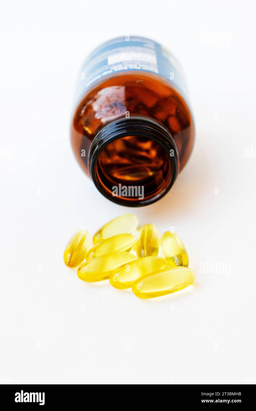 Pile of yellow fish oil capsules and pill glass bottle, fish oil