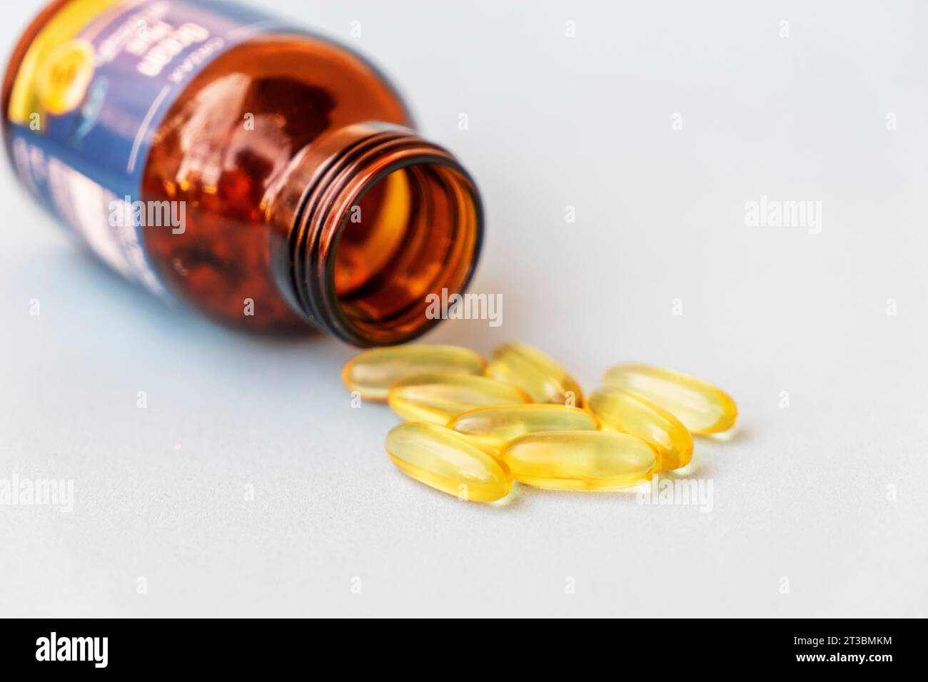 Pile of yellow fish oil capsules and pill glass bottle, fish oil