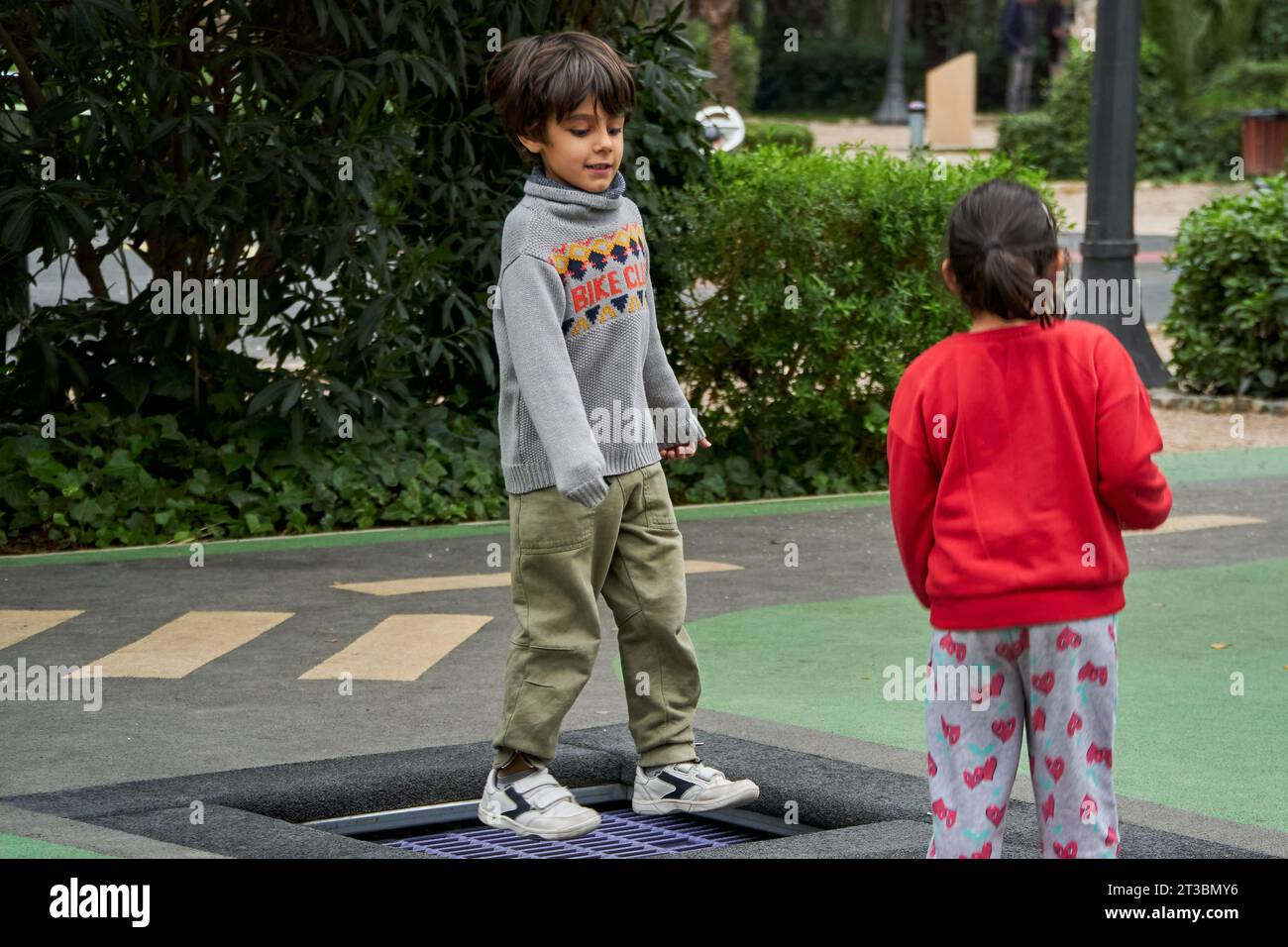 Happy boy and girl jumping together on trampoline Stock Photo - Alamy