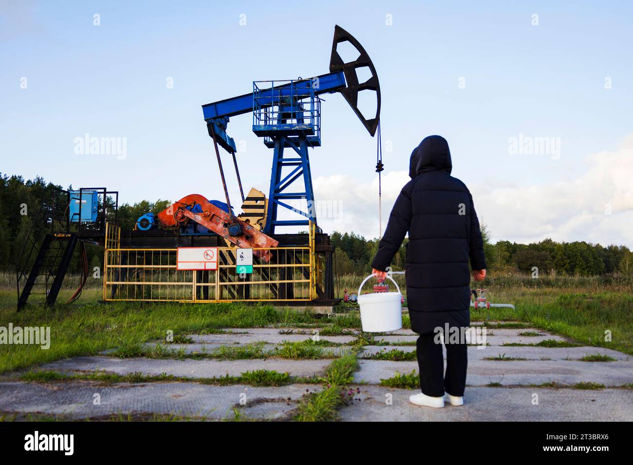 a man with an empty bucket near an oil rig. Oil crisis, oil shortage ...