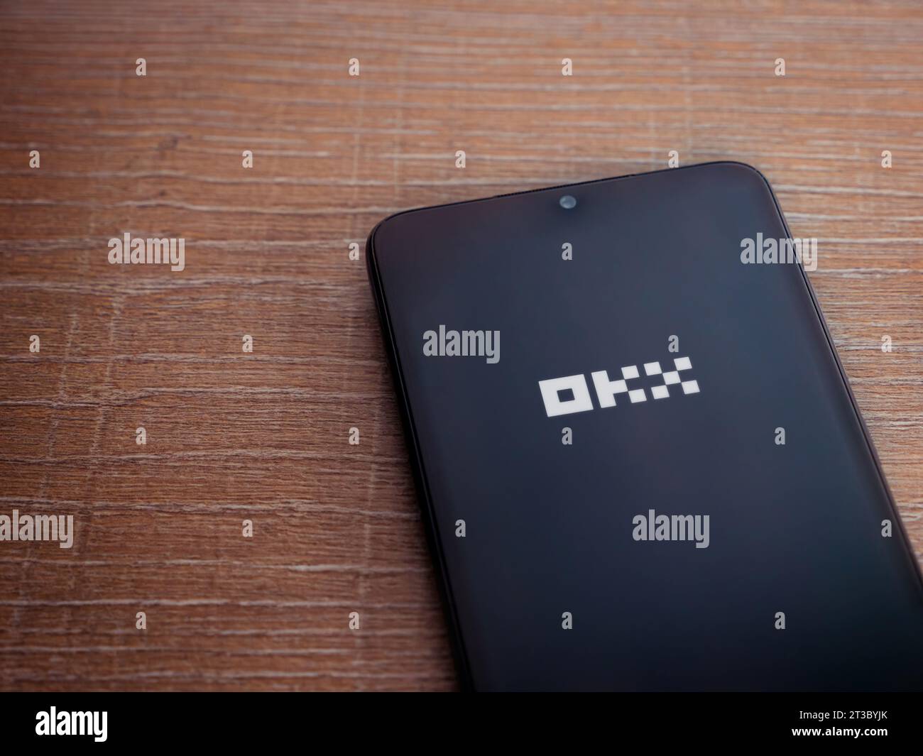 Lod, Israel - July 16,2023: OKX app launch screen on smartphone on wooden background. Top view flat lay with copy space. Stock Photo