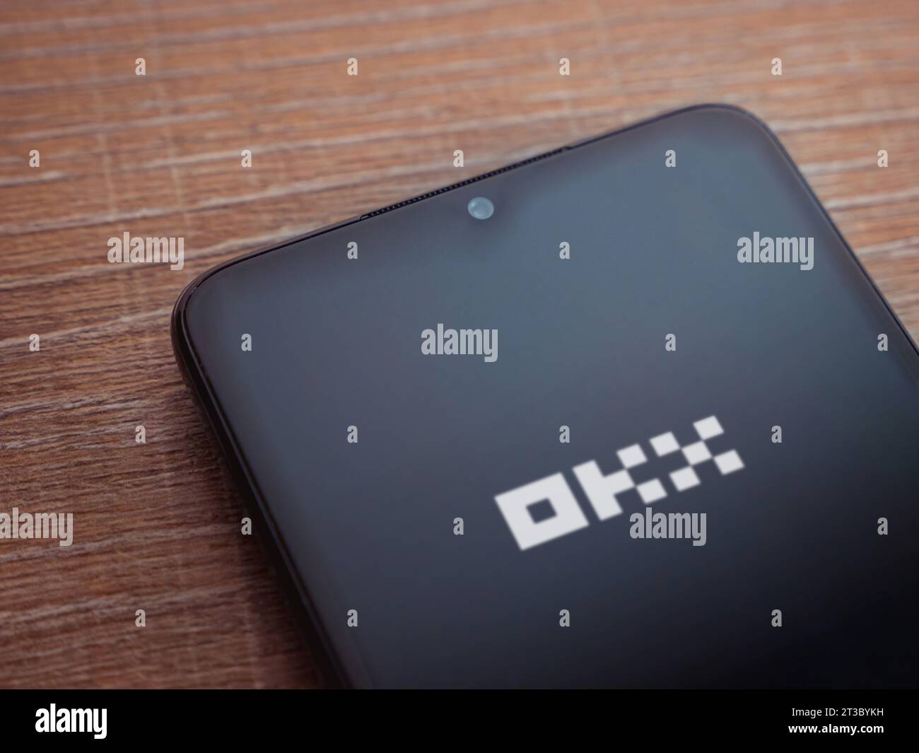 Lod, Israel - July 16,2023: OKX app launch screen on smartphone on wooden background. Top view flat lay with copy space. Stock Photo