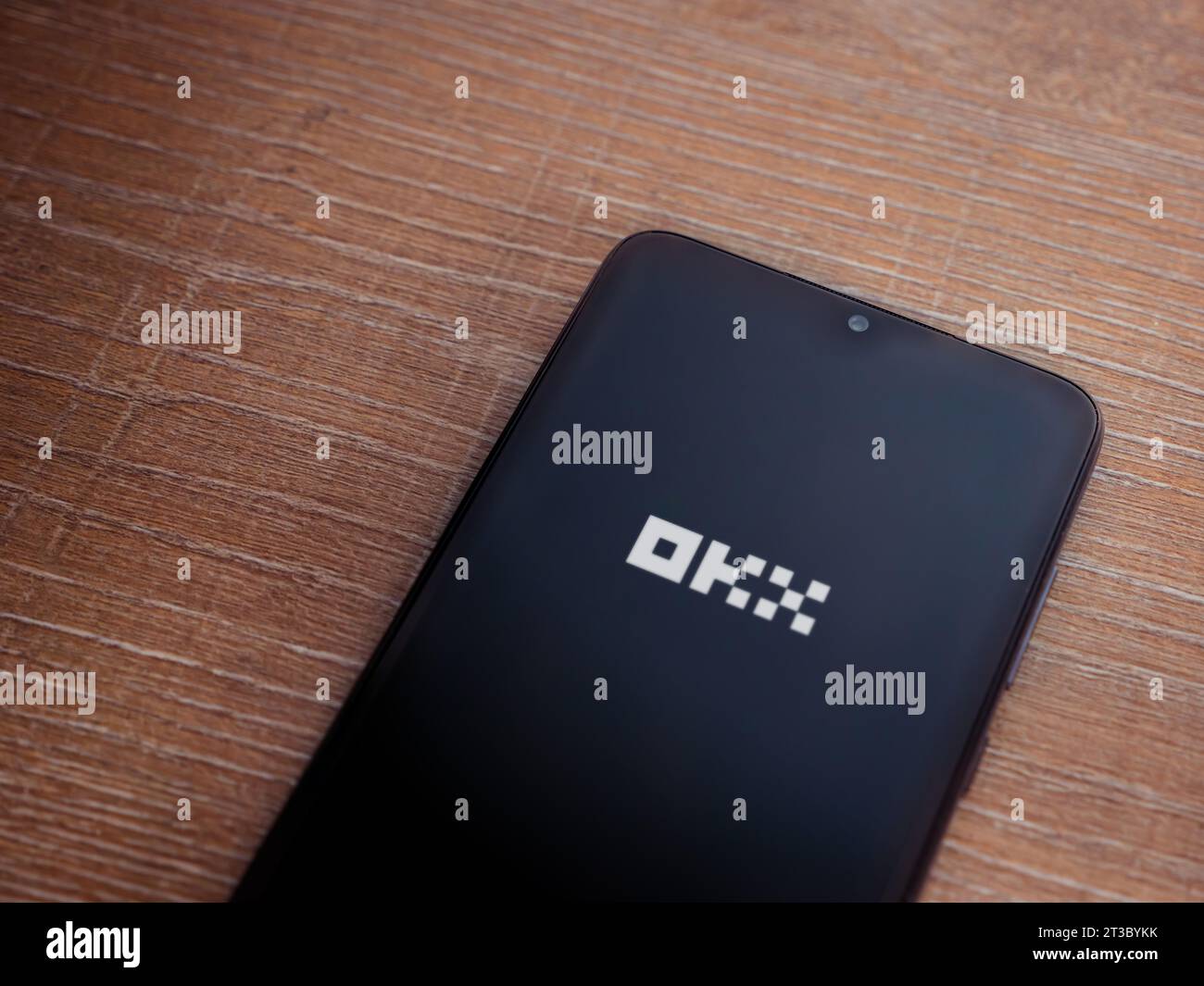 Lod, Israel - July 16,2023: OKX app launch screen on smartphone on wooden background. Top view flat lay with copy space. Stock Photo