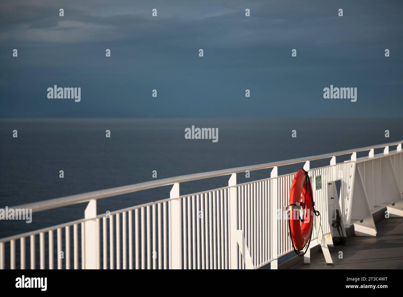 Ferry railing with  lifebuoy ring against a dramatic sky and dark ocean Stock Photo