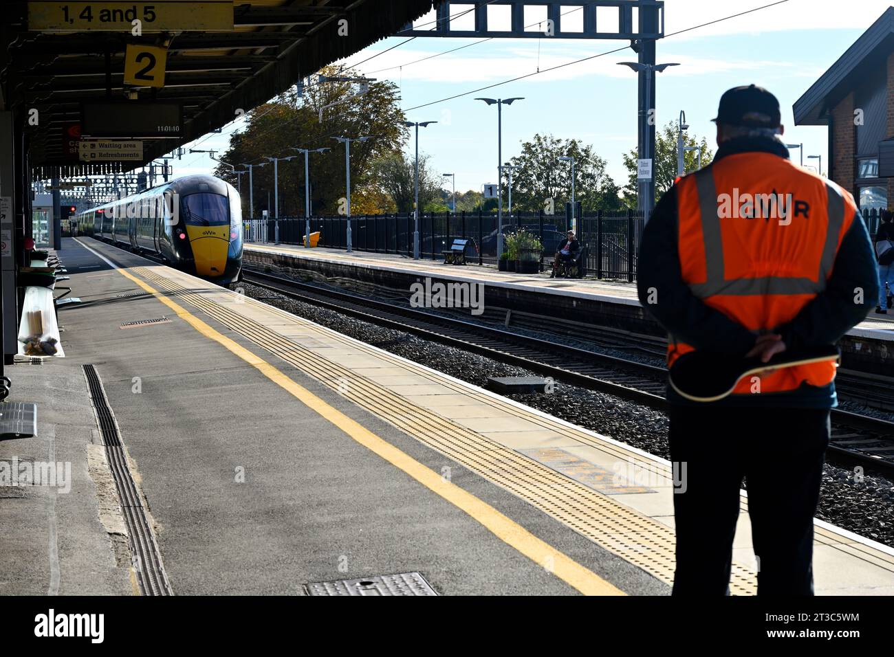 Train departing from station with GWR guard standing watching, UK Stock