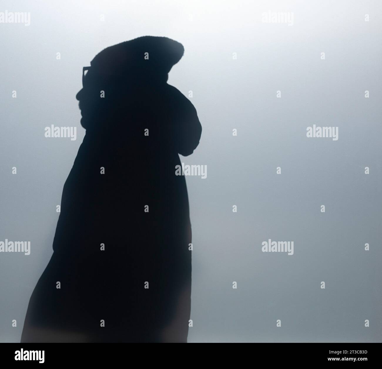 Silhouette of man viewed through frosted window dressed in parka with ...