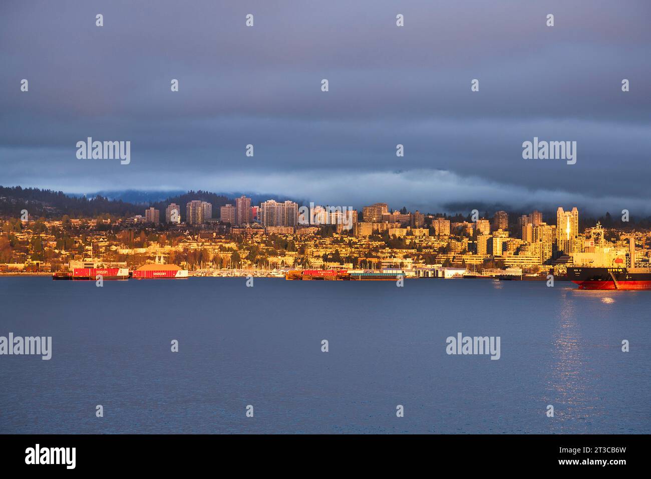 Sunlit seaside cityscape with ominous skies, North Vancouver, British Columbia, Canada Stock Photo