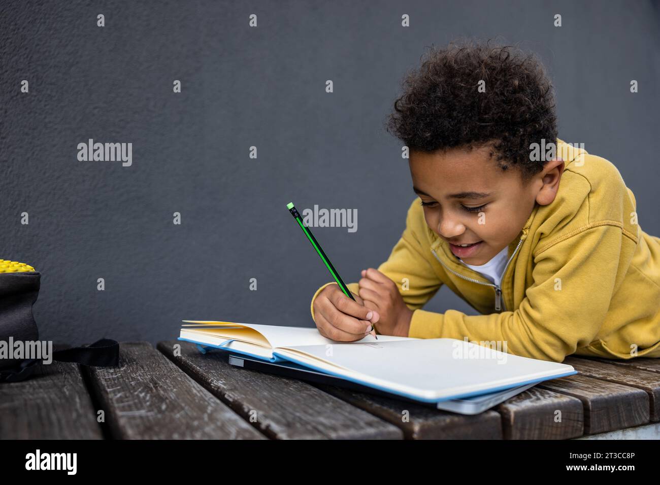 Schoolboy in yellow hoodie looking involved while doing homework Stock ...