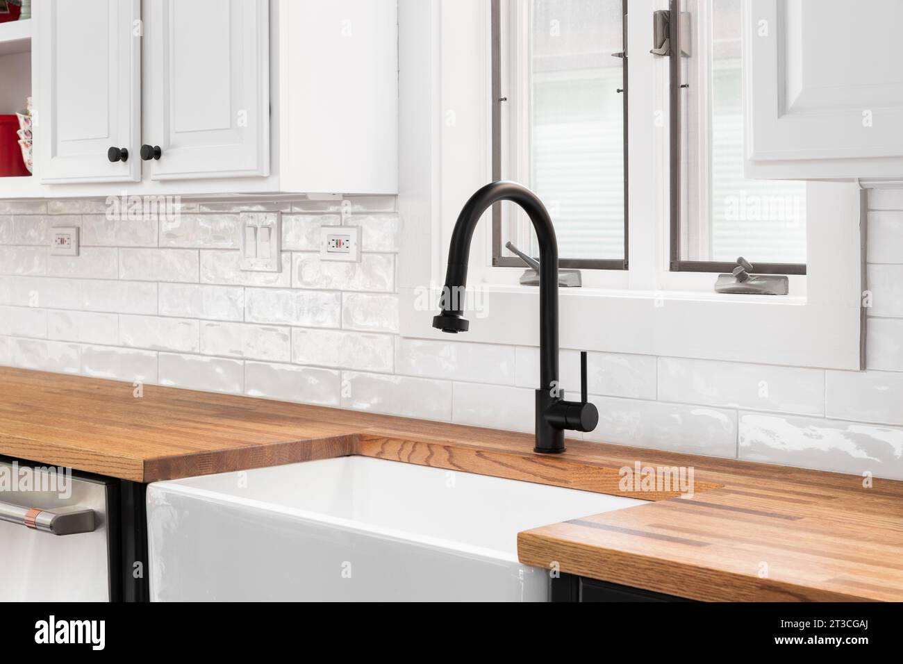 A kitchen faucet detail with white a butcher block countertop