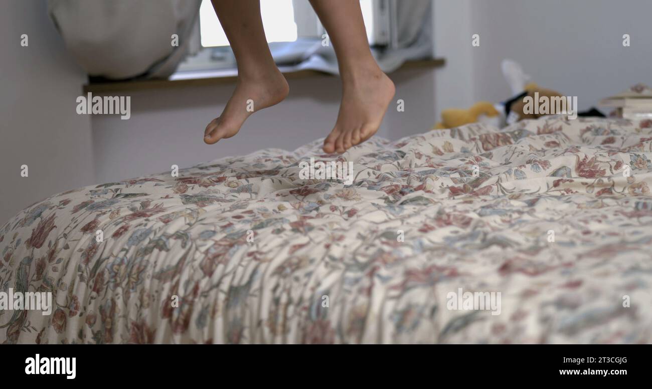 Kid feet jumping in bed sheet in super slow-motion, child legs landing on bedside playing at home, chilldhood concept captured in 800 fps-SD Stock Photo