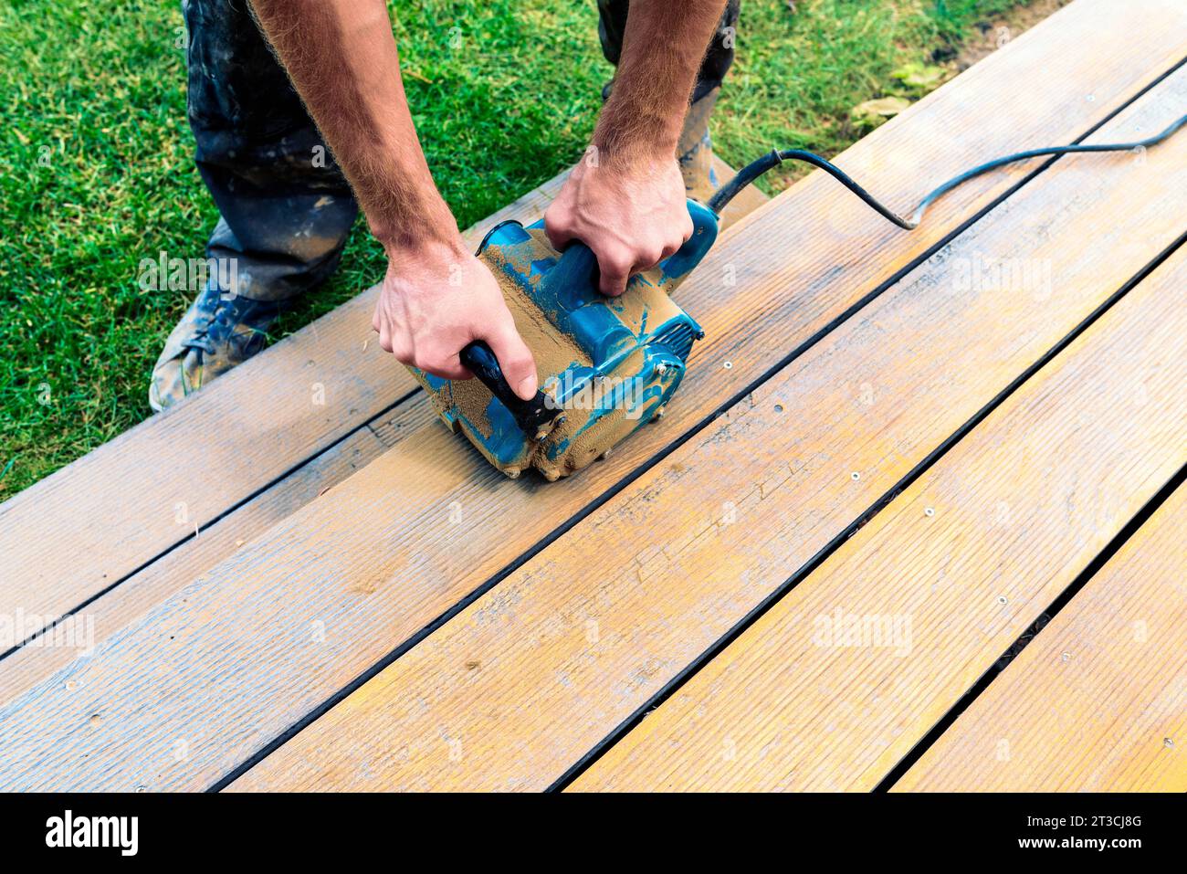 Machine cleaning of a wooden terrace - dry method - grinding the boards with handy sanding machine, preparing for oiling the terrace Stock Photo