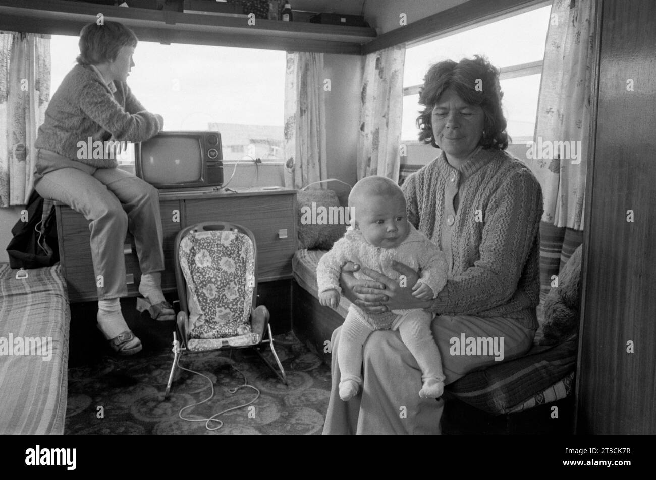 Gypsy grandmother and baby granddaughter, interior of caravan with TV set. Appleby in Westmorland gypsy horse fair Cumbria, England circa June 1981 1980s UK HOMER SYKES Stock Photo