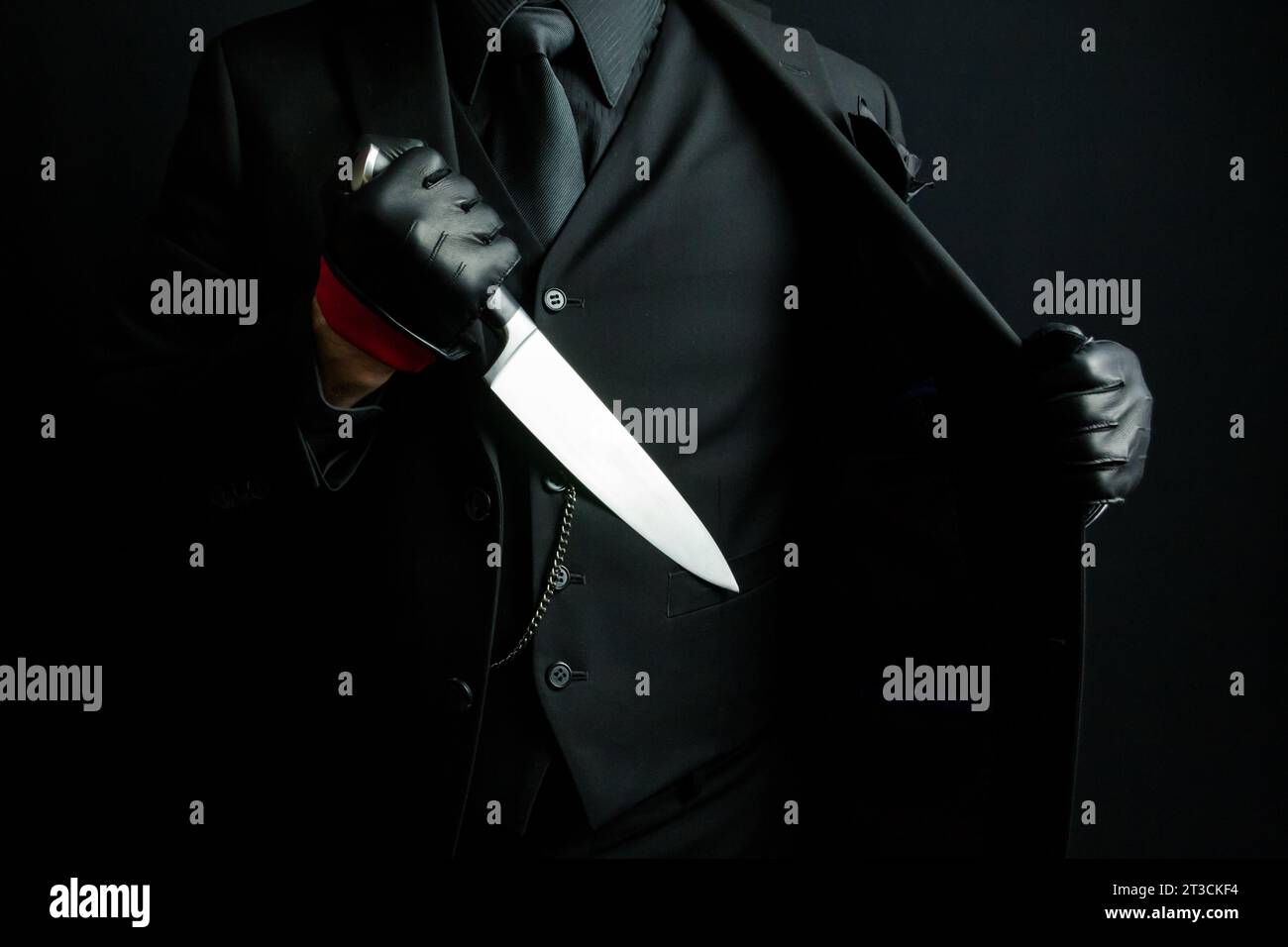Portrait of Mystery Man in Black Suit Pulling Out Knife From Jacket. Horror Movie Killer Stock Photo