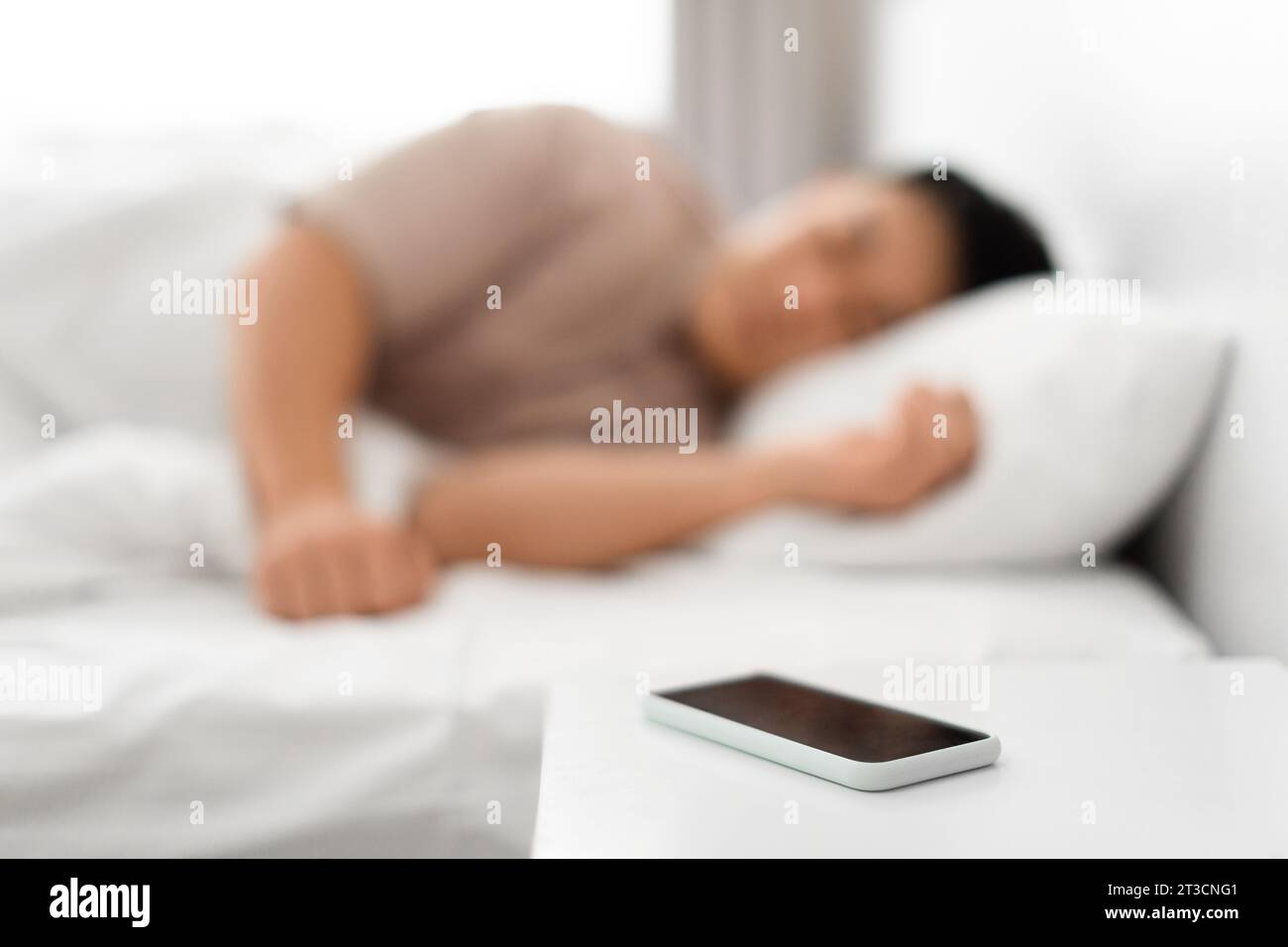 Asian man sleeping through ringing phone in the morning Stock Photo