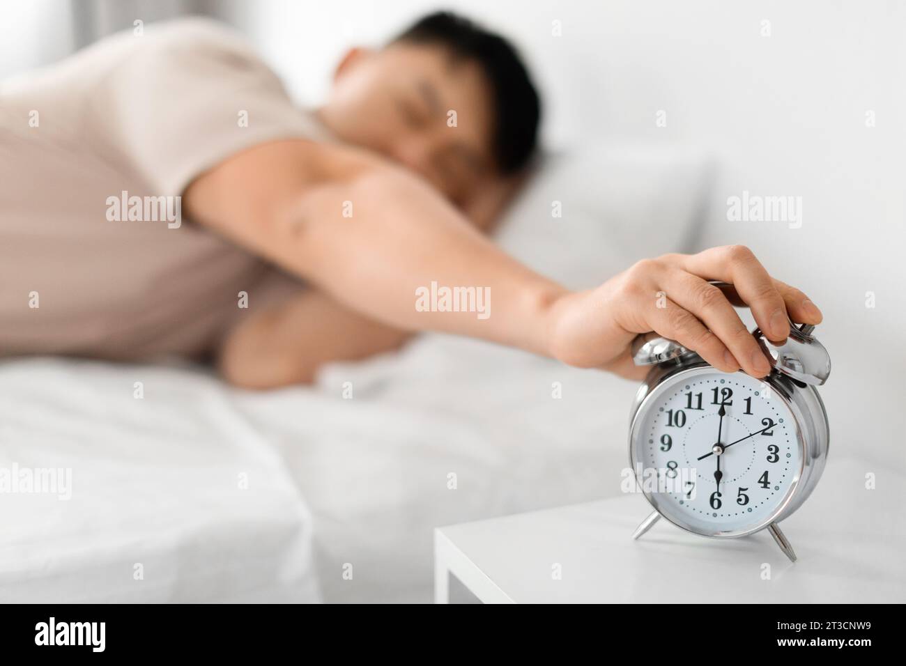 Sleepy Mature Asian Man Turning Off Alarm Clock Stock Photo
